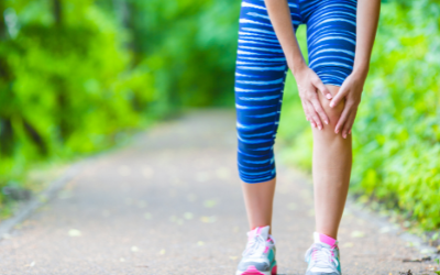 Woman walking on trail grabbing her right knee due to pain