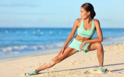 Woman performing a Hip Adductor Stretch on beach