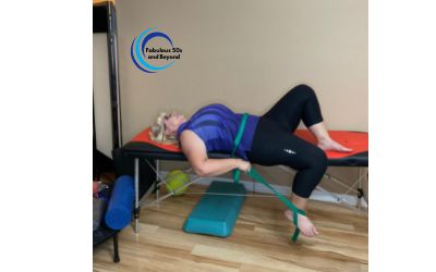 Woman laying on table performing a Supine hip flexor stretch using stretch out strap