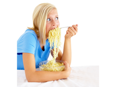 Hungry young woman stuffing her face with pasta since she is on a severe calorie deficit diet