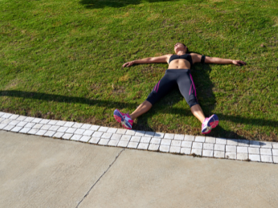 Tired female runner laying on grass field relaxing