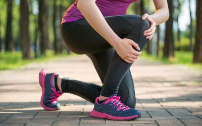 Woman kneeling on left knee on ground while grabbing right knee in pain